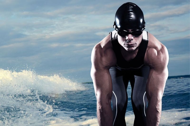 rola treningu siłowego w triathlonie - mężczyzna w kostiumie na tle morza