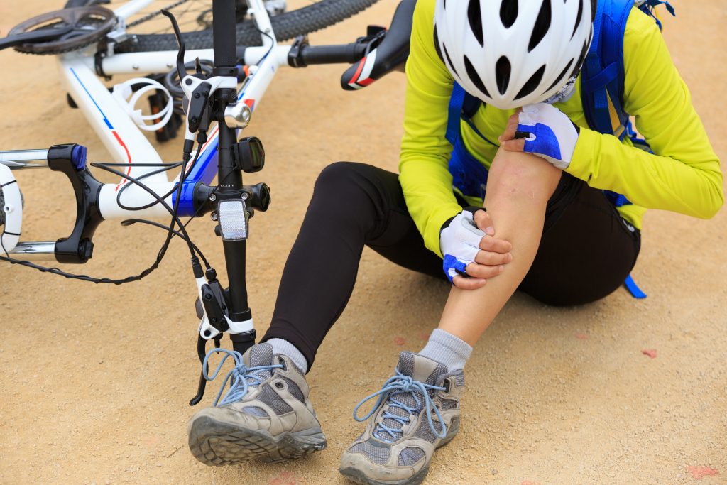 kontuzja kolarza - kolarz siedzi i obejmuje się za nogę