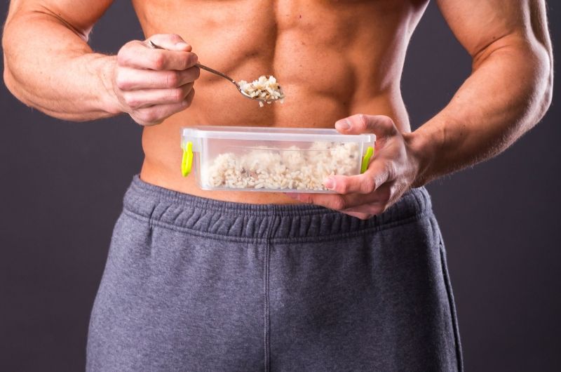 odżywianie sportowców - mężczyzna w stroju sportowym z posiłkiem w pudełku