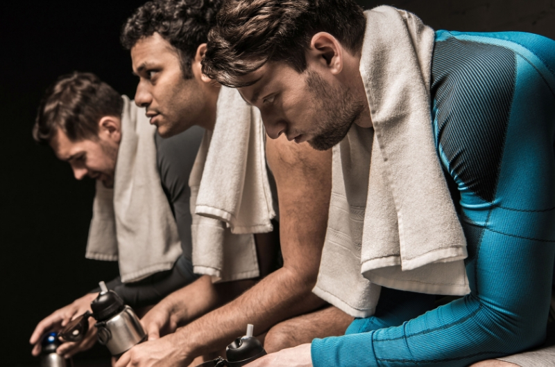 regeneracja po treningu trzech mężczyzn na ławce z ręcznikami na szyjach